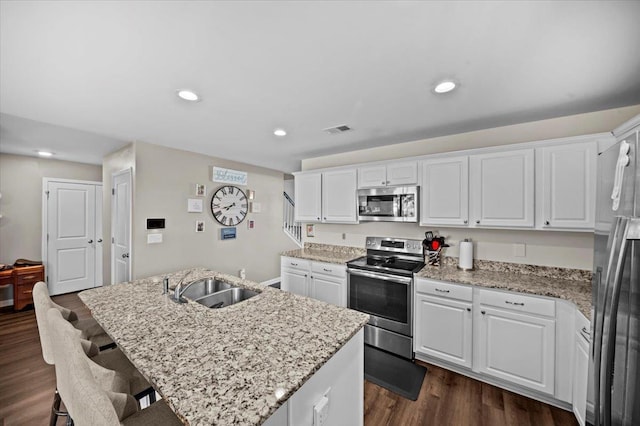 9035 Germaine Ct, Boiling Springs, SC 29316 - kitchen featuring stainless steel appliances, a kitchen island with sink, dark wood-style flooring, white cabinetry, and a kitchen bar