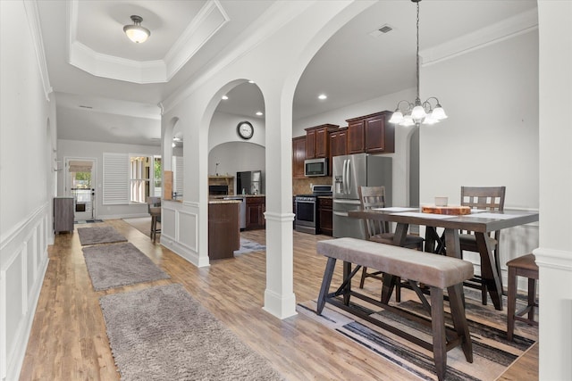 505 E Czardas Way, Woodruff, SC 29375 - dining space with a raised ceiling, light wood-style flooring, ornamental molding, a decorative wall, and arched walkways