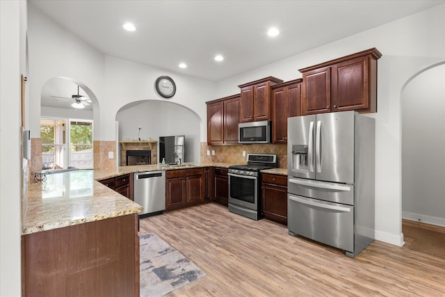 505 E Czardas Way, Woodruff, SC 29375 - kitchen featuring appliances with stainless steel finishes, arched walkways, light stone counters, ceiling fan, and light wood-type flooring