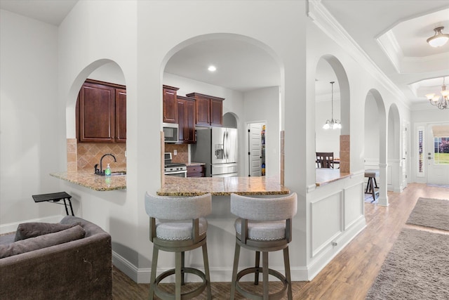 505 E Czardas Way, Woodruff, SC 29375 - kitchen featuring appliances with stainless steel finishes, a chandelier, tasteful backsplash, light wood-type flooring, and ornamental molding