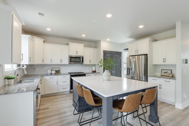 738 Judah Dr, Moore, SC 29369 - kitchen with stainless steel appliances, a breakfast bar area, decorative backsplash, a kitchen island, and white cabinetry