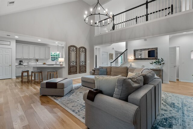5 Modesto Ln, Simpsonville, SC 29681 - living room featuring high vaulted ceiling, light wood-style floors, a chandelier, and stairs