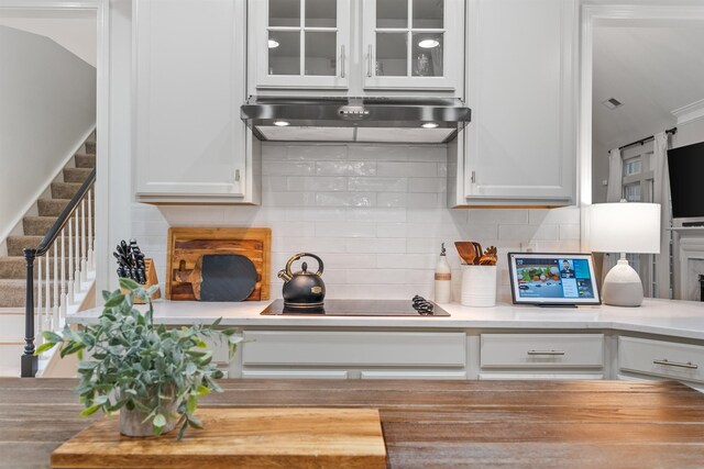 5 Modesto Ln, Simpsonville, SC 29681 - kitchen featuring under cabinet range hood, black electric stovetop, white cabinetry, and glass insert cabinets