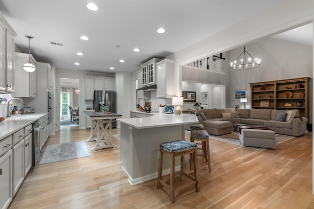 5 Modesto Ln, Simpsonville, SC 29681 - kitchen with stainless steel appliances, a chandelier, a breakfast bar, light wood-style flooring, and a peninsula