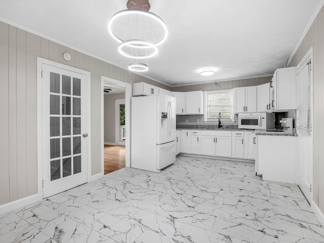 177 Continental Dr, Spartanburg, SC 29302 - kitchen featuring white appliances, light marble finish flooring, ornamental molding, white cabinets, and wooden walls