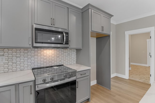 11555 New Cut Rd, Campobello, SC 29322 - kitchen with appliances with stainless steel finishes, gray cabinetry, ornamental molding, light stone counters, and tasteful backsplash
