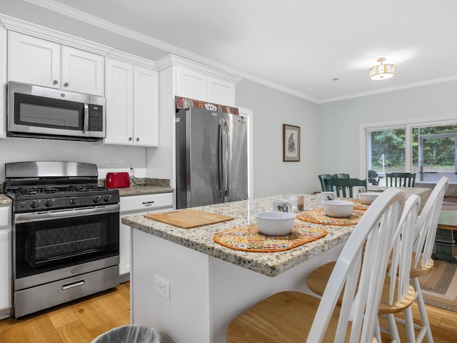 234 Page Creek Blvd, Landrum, SC 29356 - kitchen featuring appliances with stainless steel finishes, light wood-style floors, white cabinets, a center island, and crown molding