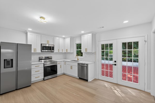 177 Lincoln Dr, Spartanburg, SC 29306 - kitchen with appliances with stainless steel finishes, light wood finished floors, decorative backsplash, white cabinetry, and french doors
