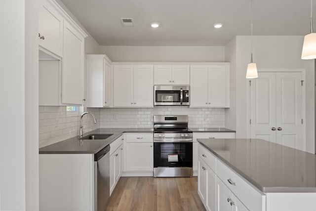1465 Macedonia Rd, Gaffney, SC 29341 - kitchen featuring stainless steel appliances, dark countertops, white cabinets, light wood-style floors, and decorative backsplash