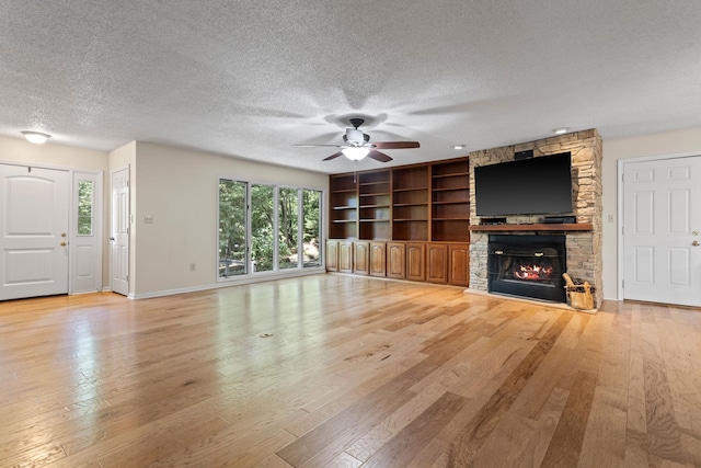 56 Cardinal Cir, Tryon, NC 28782 - unfurnished living room featuring ceiling fan, a textured ceiling, light wood finished floors, and a stone fireplace