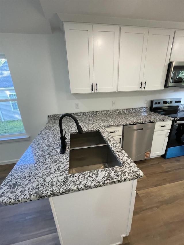 631 S Center St, Spartanburg, SC 29301 - kitchen featuring appliances with stainless steel finishes, white cabinetry, light stone countertops, dark wood-type flooring, and a peninsula