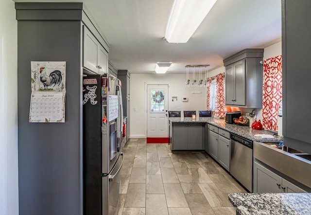 849 Harvey Rd, Greer, SC 29651 - kitchen with appliances with stainless steel finishes, gray cabinets, a peninsula, stone counters, and hanging light fixtures