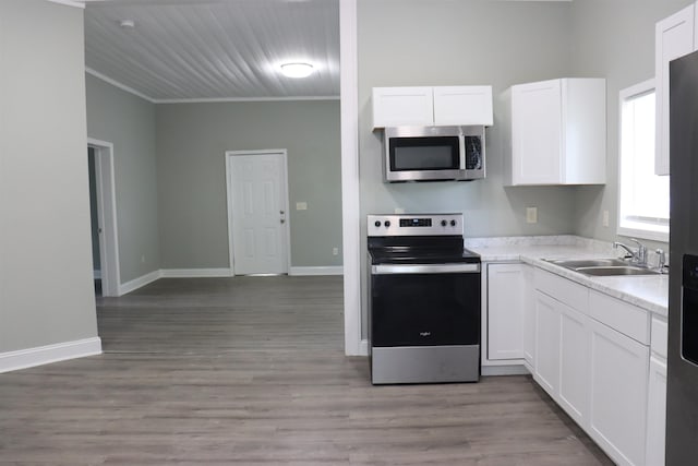 305 Spring St, Union, SC 29379 - kitchen featuring appliances with stainless steel finishes, white cabinetry, light countertops, crown molding, and light wood-style floors