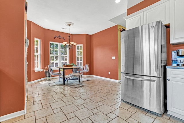 711 Waxwing Ct, Boiling Springs, SC 29316 - kitchen featuring freestanding refrigerator, white cabinets, stone tile floors, a chandelier, and pendant lighting