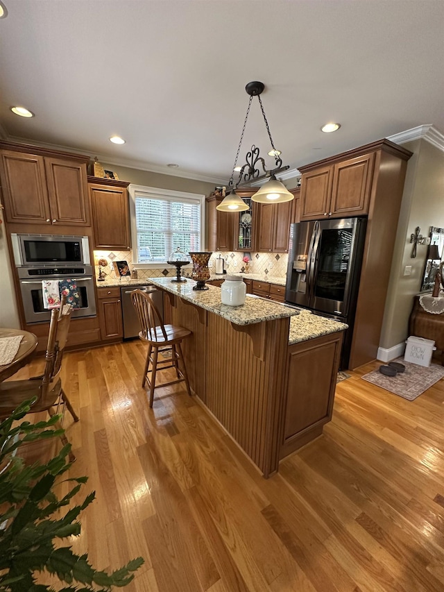 103 Welborn Oaks Way, Anderson, SC 29621 - kitchen with appliances with stainless steel finishes, ornamental molding, light wood finished floors, a kitchen bar, and a kitchen island