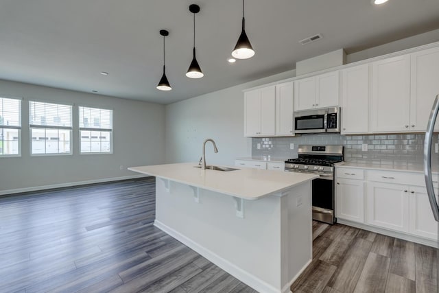 210 Wakelon Dr, Greer, SC 29651 - kitchen with appliances with stainless steel finishes, a kitchen island with sink, backsplash, wood finished floors, and light countertops