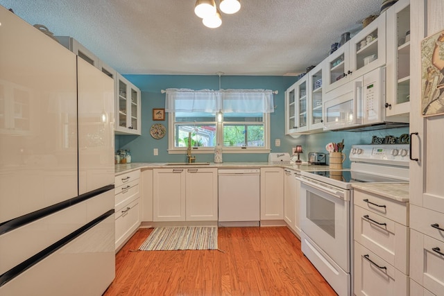 1212 Riveroak Rd, Inman, SC 29349 - kitchen with white appliances, a textured ceiling, light wood-style floors, light countertops, and glass insert cabinets