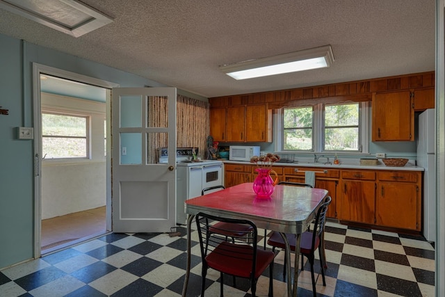 1212 Riveroak Rd, Inman, SC 29349 - kitchen with light flooring, white appliances, light countertops, brown cabinetry, and a textured ceiling