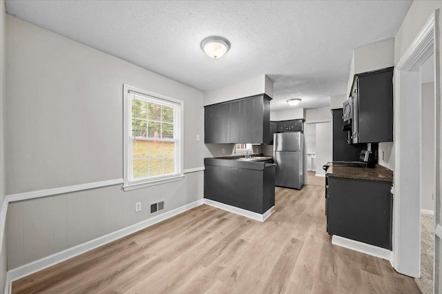 251 Winfield Dr, Spartanburg, SC 29307 - kitchen featuring freestanding refrigerator, dark countertops, light wood finished floors, a textured ceiling, and dark cabinets