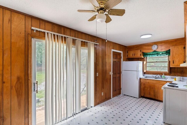 210 Catawba St, Union, SC 29379 - kitchen featuring white appliances, healthy amount of natural light, wooden walls, a textured ceiling, and brown cabinetry