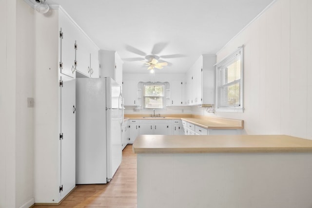 114 W Carolina St, Duncan, SC 29344 - kitchen featuring freestanding refrigerator, a peninsula, light wood-style floors, ceiling fan, and white cabinetry