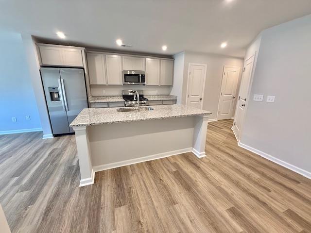 1236 Forestbrook Ln, Spartanburg, SC 29303 - kitchen featuring stainless steel appliances, an island with sink, light wood-style floors, gray cabinets, and light stone counters