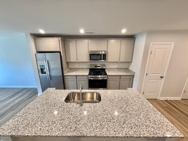 1236 Forestbrook Ln, Spartanburg, SC 29303 - kitchen featuring stainless steel appliances, wood finished floors, light stone countertops, an island with sink, and recessed lighting