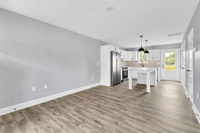 938 Logan St, Spartanburg, SC 29306 - kitchen featuring appliances with stainless steel finishes, light countertops, decorative backsplash, white cabinetry, and light wood finished floors
