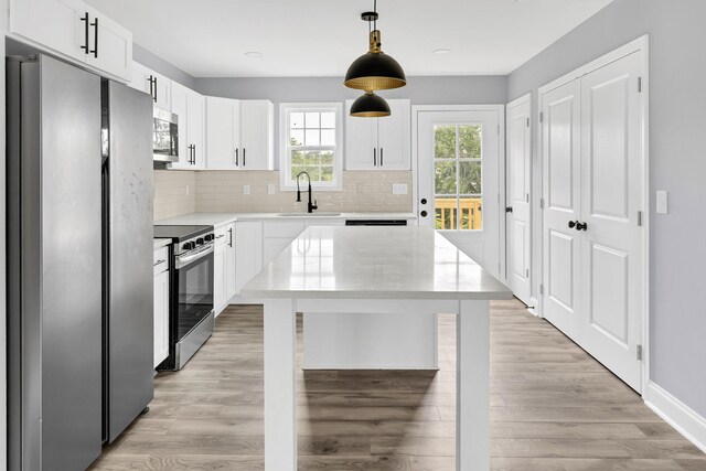 938 Logan St, Spartanburg, SC 29306 - kitchen featuring stainless steel appliances, tasteful backsplash, light wood-type flooring, decorative light fixtures, and white cabinets