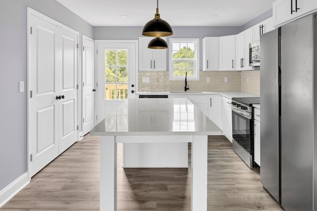 938 Logan St, Spartanburg, SC 29306 - kitchen with appliances with stainless steel finishes, tasteful backsplash, white cabinets, decorative light fixtures, and a center island