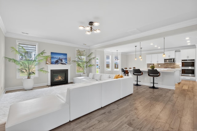 3027 Toliver, Boiling Springs, SC 29316 - living area with light wood-style flooring, crown molding, a fireplace with flush hearth, recessed lighting, and a chandelier