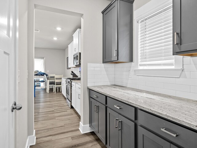 1116 Denington Dr, Spartanburg, SC 29307 - kitchen featuring appliances with stainless steel finishes, gray cabinetry, light wood-style flooring, decorative backsplash, and light stone counters