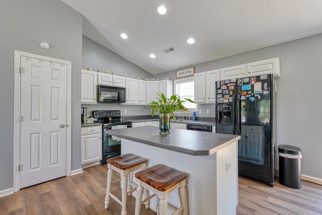 286 Heatherbrook Dr, Lyman, SC 29365 - kitchen with black appliances, white cabinetry, dark countertops, a kitchen breakfast bar, and light wood-style flooring