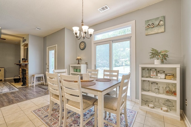316 Crestview Ln, Spartanburg, SC 29301 - dining area featuring light tile patterned flooring, a chandelier, a fireplace, and a textured ceiling