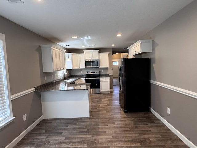 313 Trail Crossing Ln, Inmann, SC 29349 - kitchen with appliances with stainless steel finishes, a peninsula, dark wood-type flooring, white cabinetry, and recessed lighting