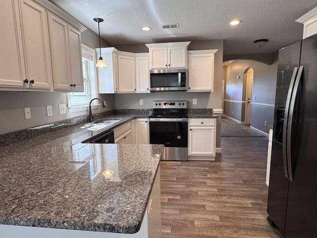 313 Trail Crossing Ln, Inmann, SC 29349 - kitchen with stainless steel appliances, arched walkways, a textured ceiling, dark wood-type flooring, and decorative light fixtures