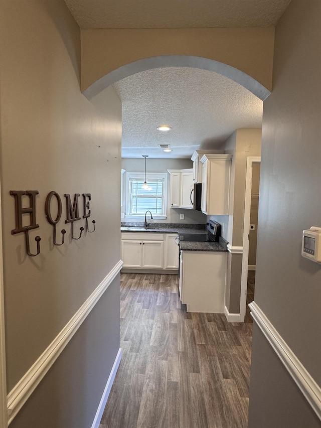 313 Trail Crossing Ln, Inmann, SC 29349 - kitchen featuring appliances with stainless steel finishes, arched walkways, a textured ceiling, white cabinets, and dark wood-style floors