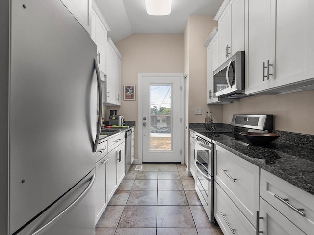 135 N Fairview Ave, Spartanburg, SC 29302 - kitchen with appliances with stainless steel finishes, white cabinets, lofted ceiling, dark stone countertops, and light tile patterned floors