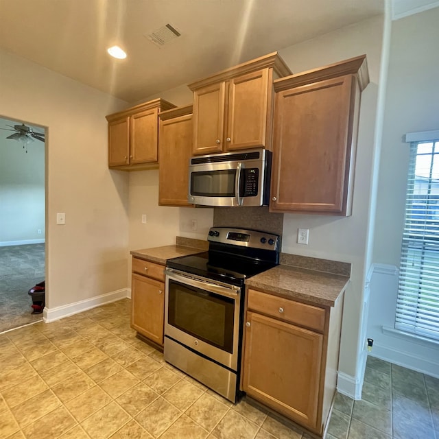 240 Stonecrest Dr, Roebuck, SC 29376 - kitchen featuring stainless steel appliances, a ceiling fan, dark countertops, and brown cabinets