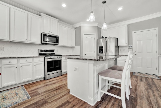 332 Heritage Point Dr, Simpsonville, SC 29681 - kitchen featuring appliances with stainless steel finishes, crown molding, wood finished floors, white cabinets, and a center island