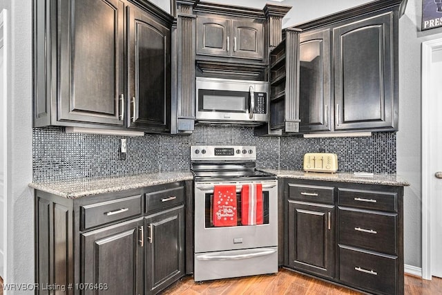 kitchen with tasteful backsplash, light stone countertops, stainless steel appliances, and light hardwood / wood-style floors