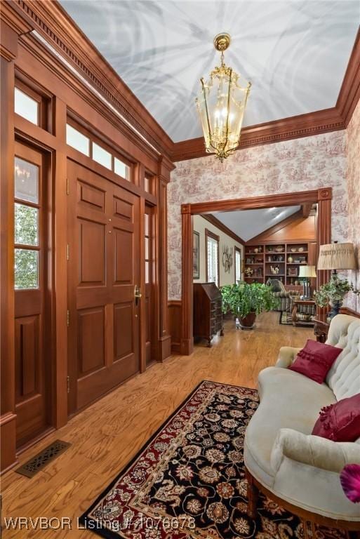 entrance foyer featuring crown molding, hardwood / wood-style floors, and a notable chandelier