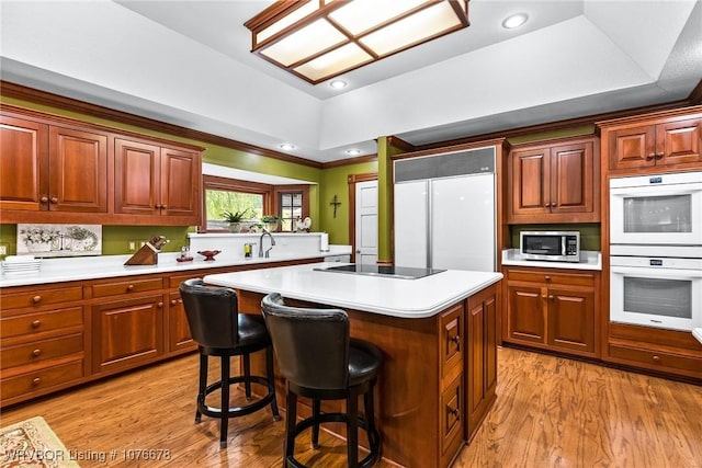 kitchen with a tray ceiling, a center island, double oven, and black electric stovetop