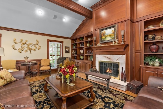 living room featuring built in shelves, a high end fireplace, lofted ceiling, hardwood / wood-style flooring, and ornamental molding