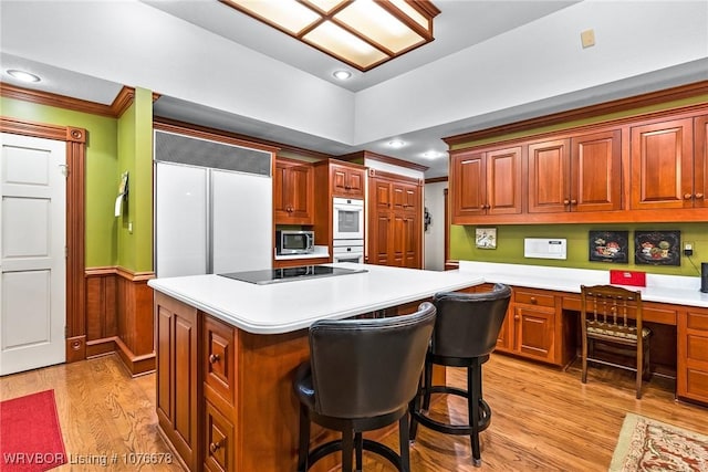 kitchen featuring a kitchen breakfast bar, light hardwood / wood-style flooring, double oven, crown molding, and built in desk