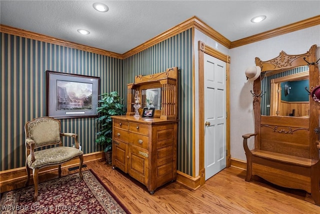 living area with a textured ceiling, light hardwood / wood-style floors, and crown molding