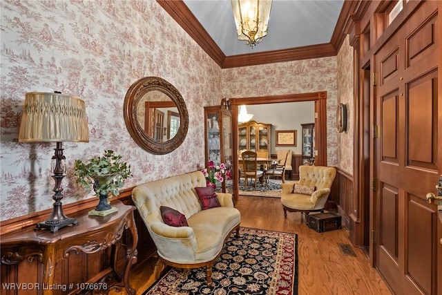 sitting room featuring light hardwood / wood-style flooring, crown molding, and a notable chandelier