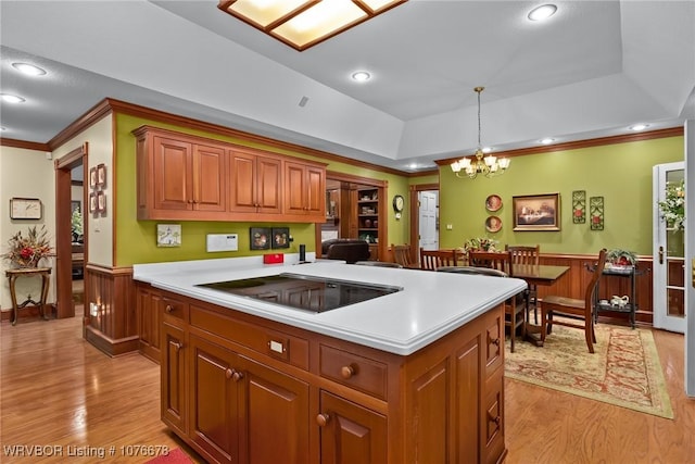 kitchen featuring a tray ceiling, electric stovetop, light hardwood / wood-style flooring, a chandelier, and hanging light fixtures