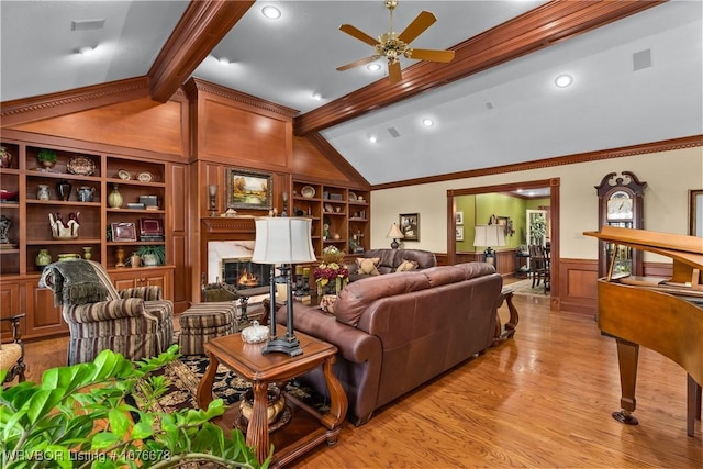 living room featuring ceiling fan, built in features, crown molding, light hardwood / wood-style floors, and a fireplace