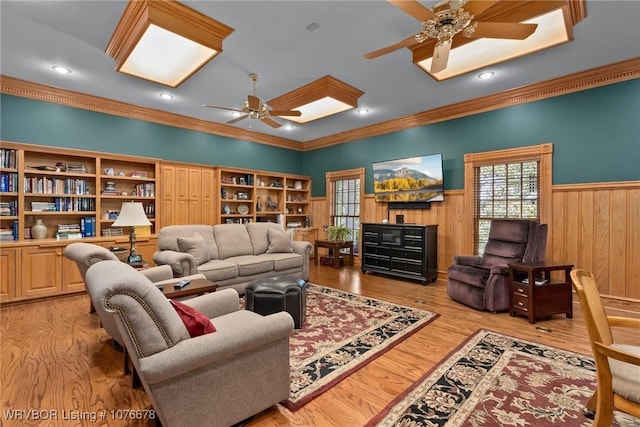 living room featuring ceiling fan, built in features, ornamental molding, and light hardwood / wood-style flooring